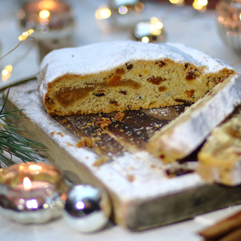 loaf of stollen on a wooden board with twinkly christmas lights